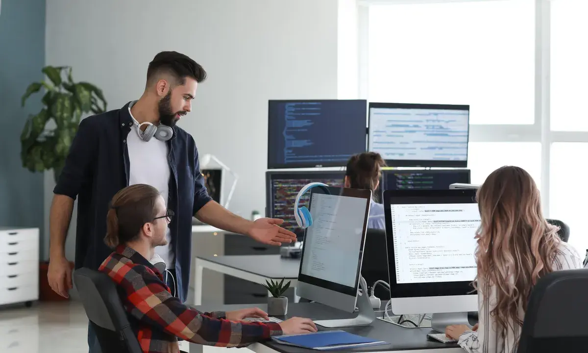 Un lead developer discute du code avec un collègue, peut-être pour négocier son salaire.