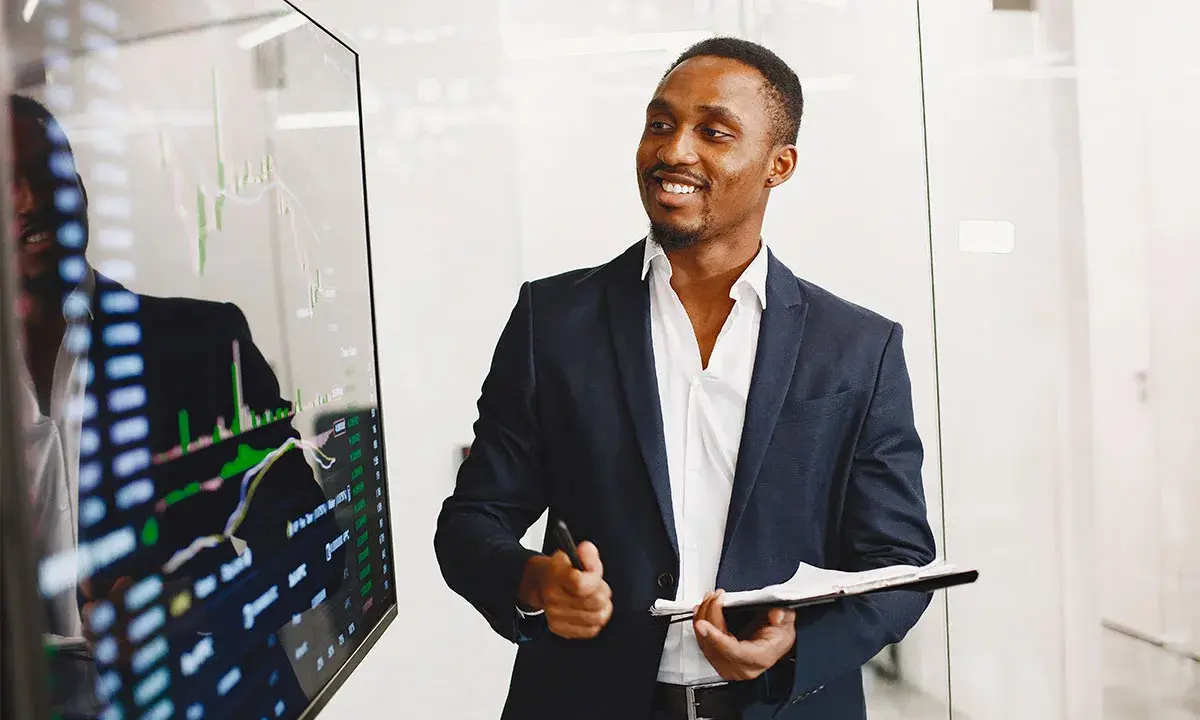 Un key account executive souriant présente des graphiques financiers sur un écran.