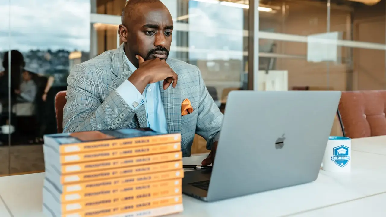 Un consultant référencement Google analyse des données sur son ordinateur portable, entouré de livres et d'une tasse Bix Academy.