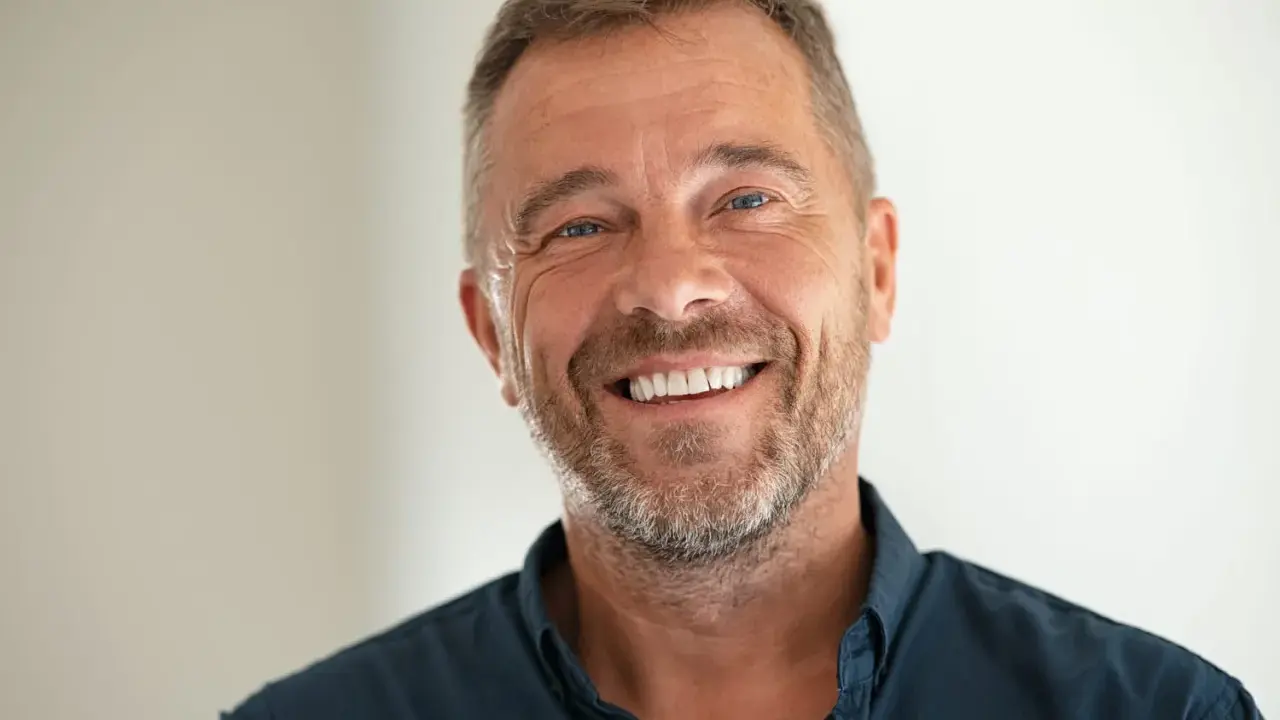 Un homme souriant, le chef de cabinet du PDG, avec une barbe poivre et sel et des yeux bleus pétillants.