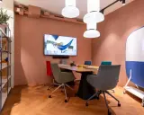 Aménagement de locaux professionnels : salle de réunion moderne avec table, chaises colorées, écran et tableau blanc mobile.