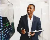 Un key account executive souriant présente des graphiques financiers sur un écran.
