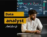 Un homme concentré sur son ordinateur portable, prêt à devenir data analyst. Graphiques financiers en arrière-plan.