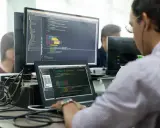 Un développeur Ruby on Rails concentré sur son code, devant plusieurs écrans affichant des lignes de programmation.