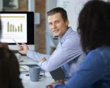 Un consultant en communication digitale explique des graphiques à ses collègues lors d'une réunion.