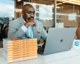 Un consultant référencement Google analyse des données sur son ordinateur portable, entouré de livres et d'une tasse Bix Academy.