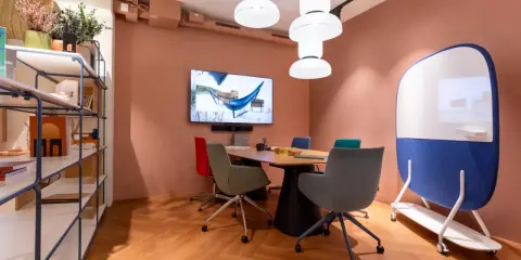 Aménagement de locaux professionnels : salle de réunion moderne avec table, chaises colorées, écran et tableau blanc mobile.