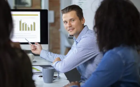 Un consultant en communication digitale explique des graphiques à ses collègues lors d'une réunion.