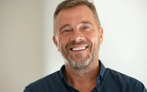 Un homme souriant, le chef de cabinet du PDG, avec une barbe poivre et sel et des yeux bleus pétillants.