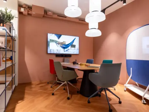 Aménagement de locaux professionnels : salle de réunion moderne avec table, chaises colorées, écran et tableau blanc mobile.