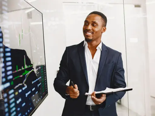Un key account executive souriant présente des graphiques financiers sur un écran.