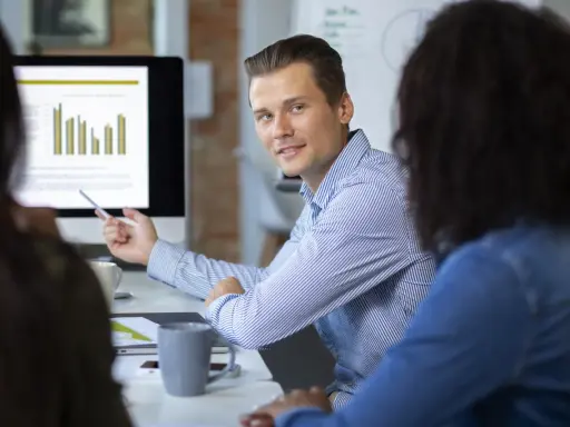Un consultant en communication digitale explique des graphiques à ses collègues lors d'une réunion.