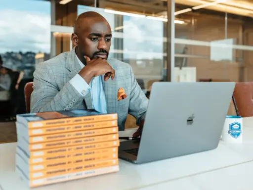 Un consultant référencement Google analyse des données sur son ordinateur portable, entouré de livres et d'une tasse Bix Academy.