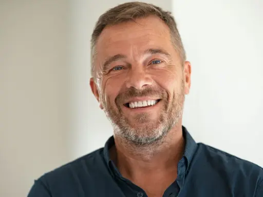 Un homme souriant, le chef de cabinet du PDG, avec une barbe poivre et sel et des yeux bleus pétillants.