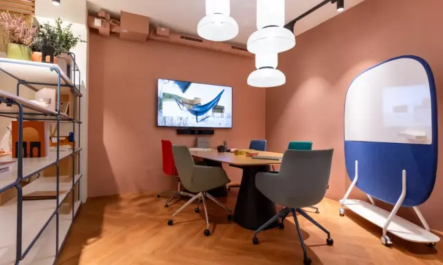 Aménagement de locaux professionnels : salle de réunion moderne avec table, chaises colorées, écran et tableau blanc mobile.