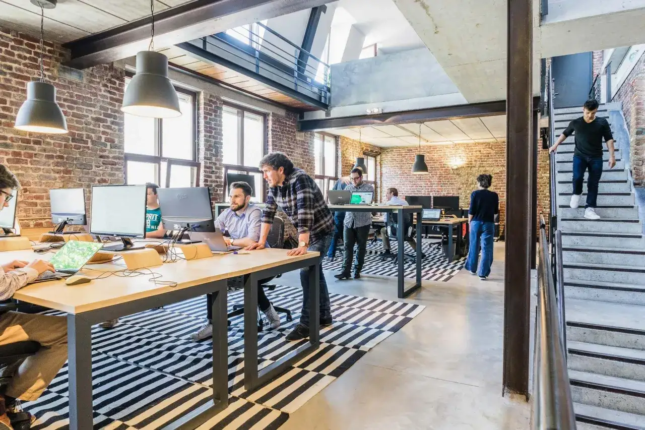 Ambiance dynamique pour travailler dans une start up : des employ&eacute;s concentr&eacute;s sur leurs &eacute;crans, un homme descendant les escaliers.