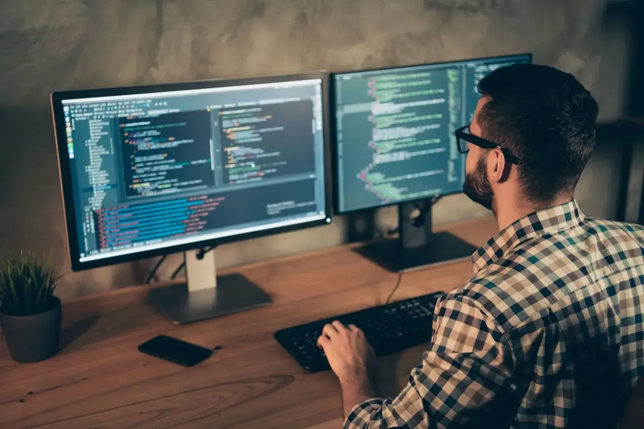Un d&eacute;veloppeur web concentr&eacute; sur ses deux &eacute;crans, un signe de recrutement actif dans le domaine.
