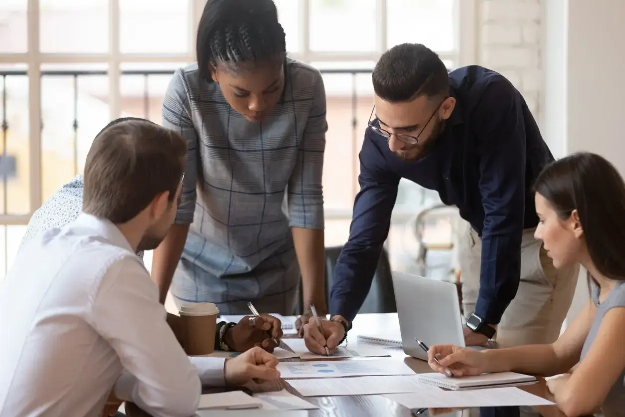 &Eacute;quipe concentr&eacute;e sur la r&eacute;solution de probl&egrave;mes, analysant des documents et collaborant autour d'une table.