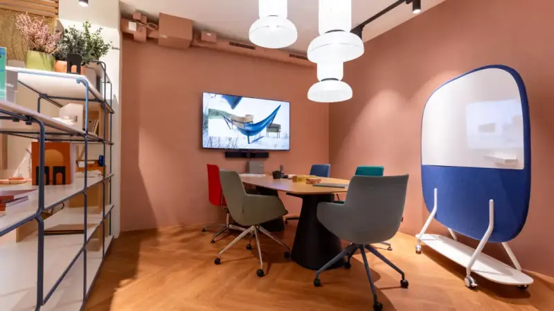 Aménagement de locaux professionnels : salle de réunion moderne avec table, chaises colorées, écran et tableau blanc mobile.